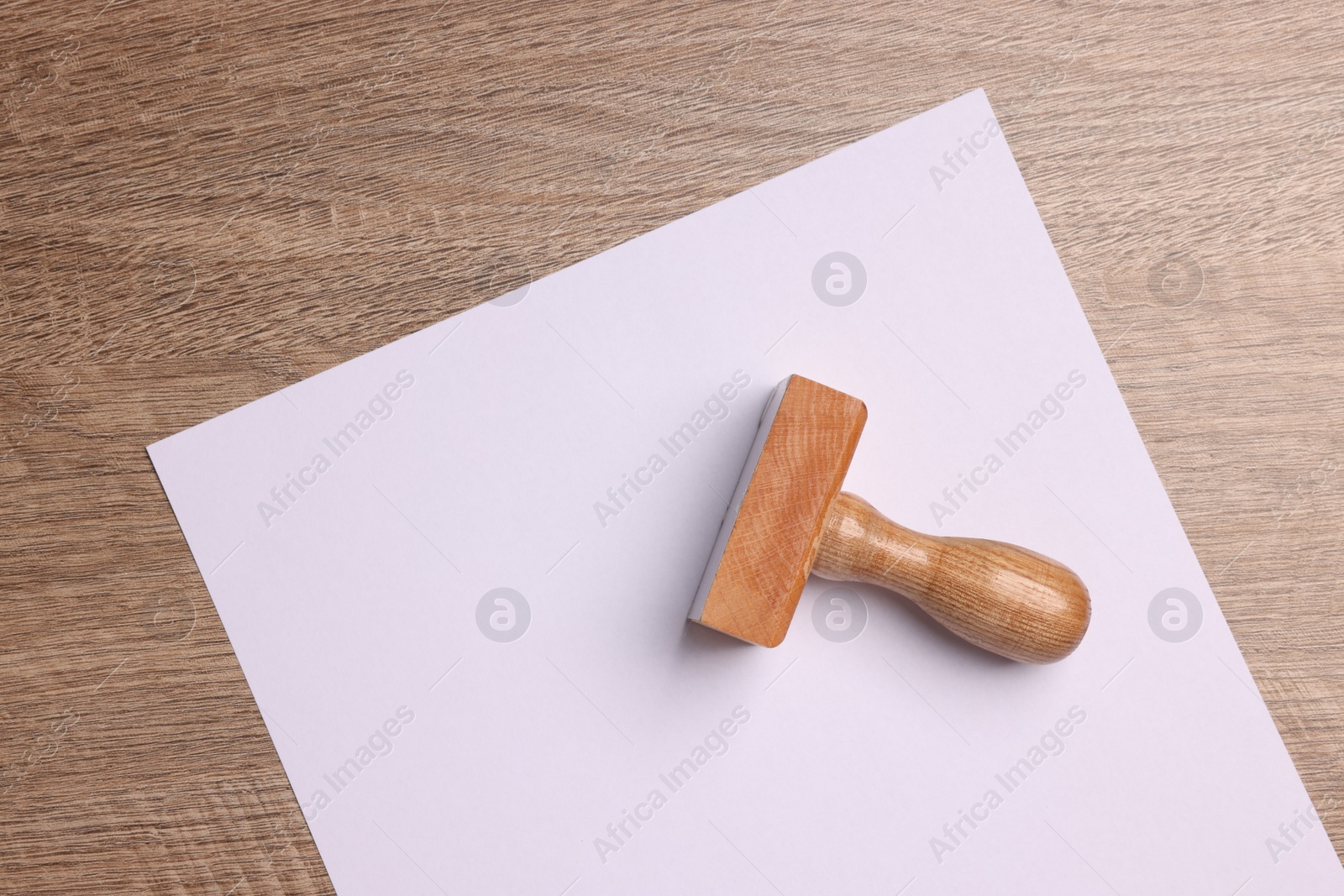 Photo of One stamp tool and sheet of paper on wooden table, top view. Space for text