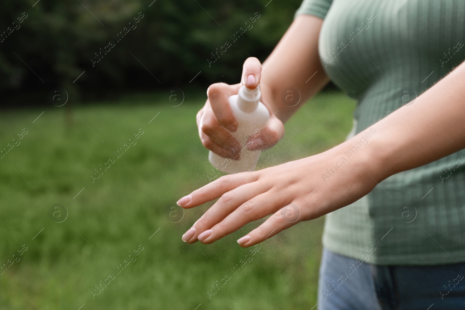 Photo of Woman applying insect repellent onto hand in park, closeup. Tick bites prevention