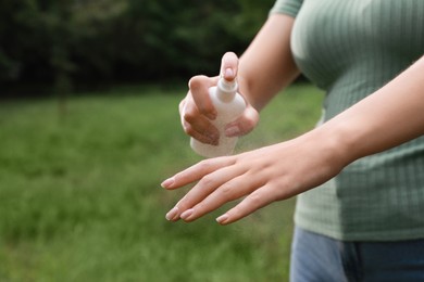 Woman applying insect repellent onto hand in park, closeup. Tick bites prevention