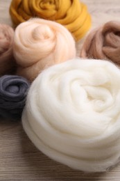 Photo of Colorful felting wool on wooden table, closeup