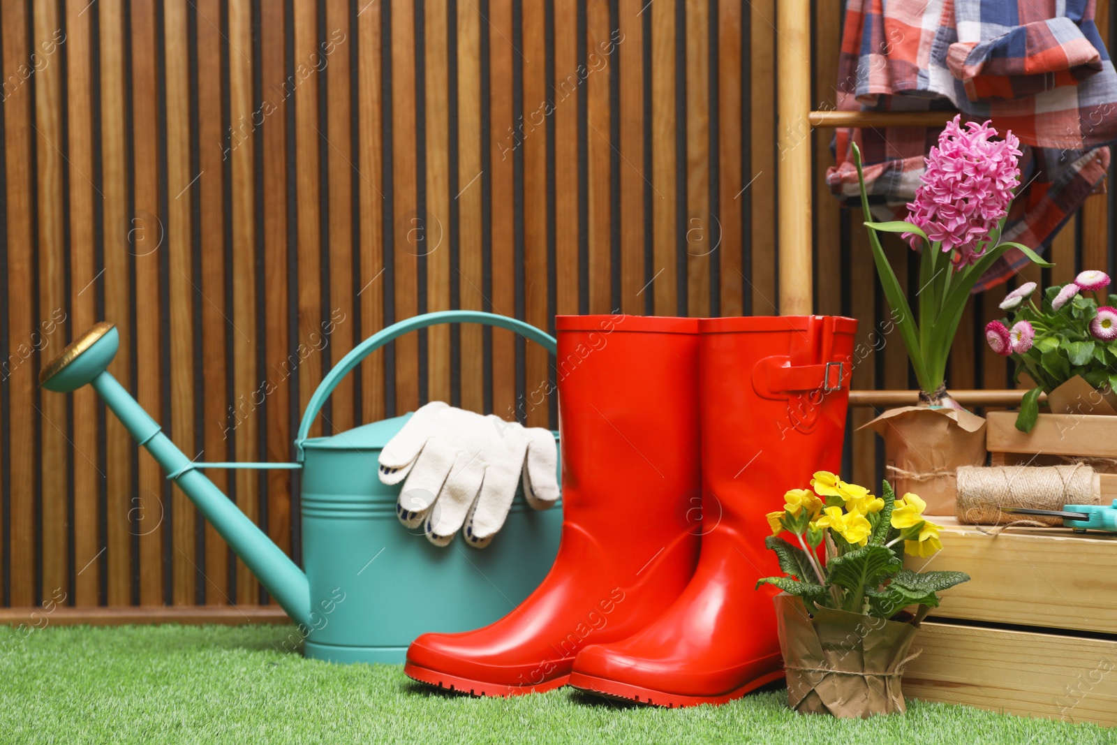 Photo of Composition with different gardening tools on artificial grass at wooden wall