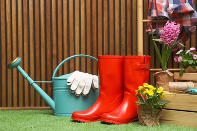 Composition with different gardening tools on artificial grass at wooden wall