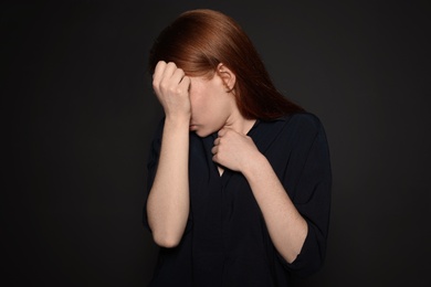 Upset young woman crying against dark background