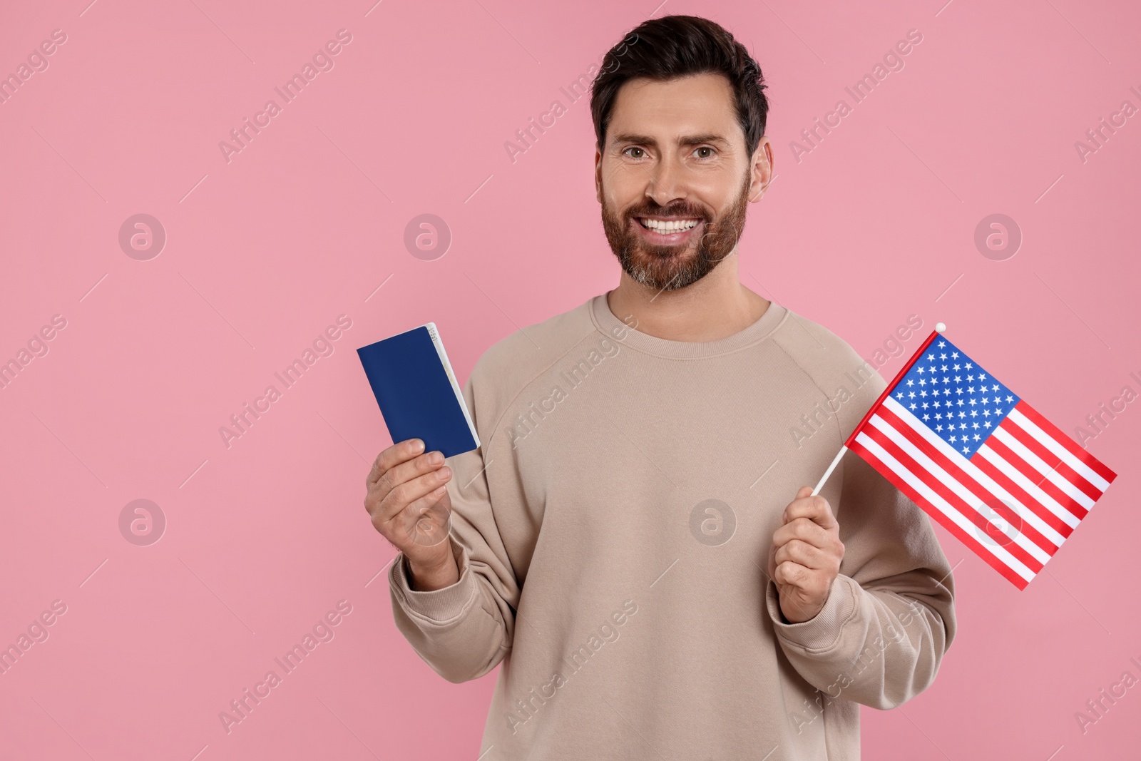 Photo of Immigration. Happy man with passport and American flag on pink background, space for text