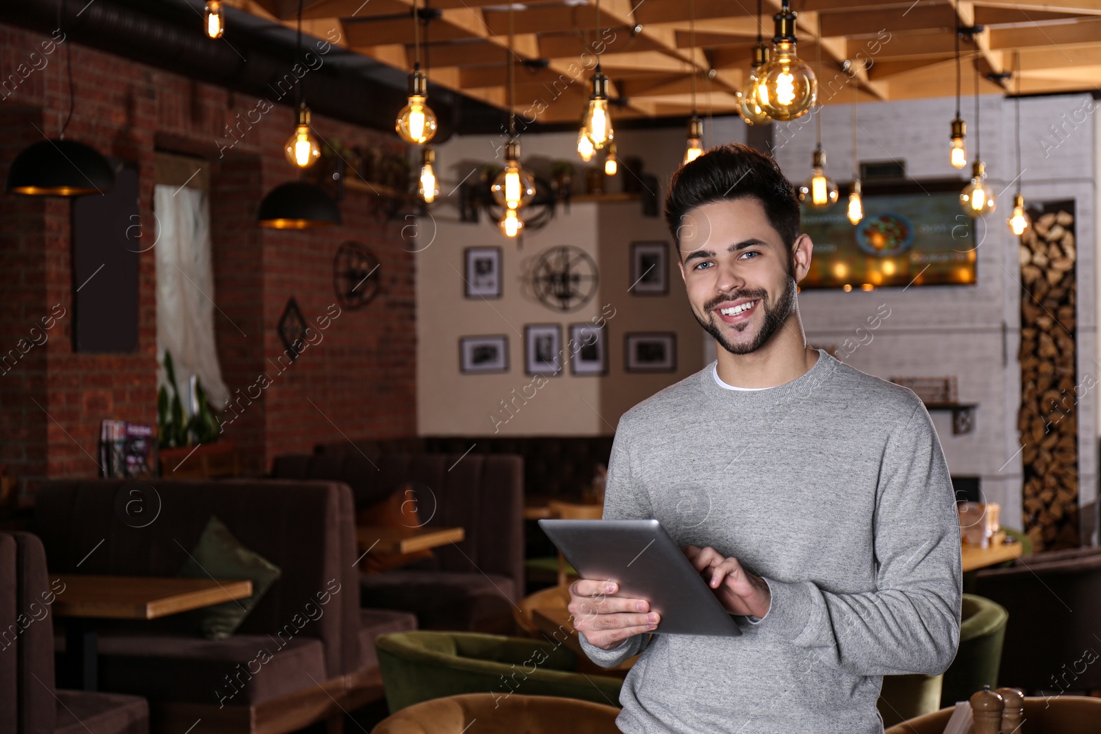 Photo of Young business owner with tablet in his cafe. Space for text