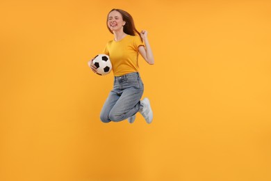 Photo of Emotional sports fan with ball jumping on yellow background