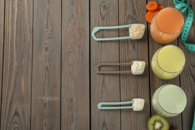 Tasty shakes, different powders, measuring tape, cut carrot and kiwi on wooden table, flat lay with space for text. Weight loss