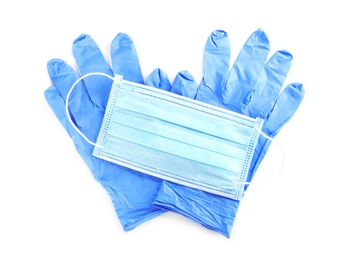 Medical gloves and protective face mask on white background, top view