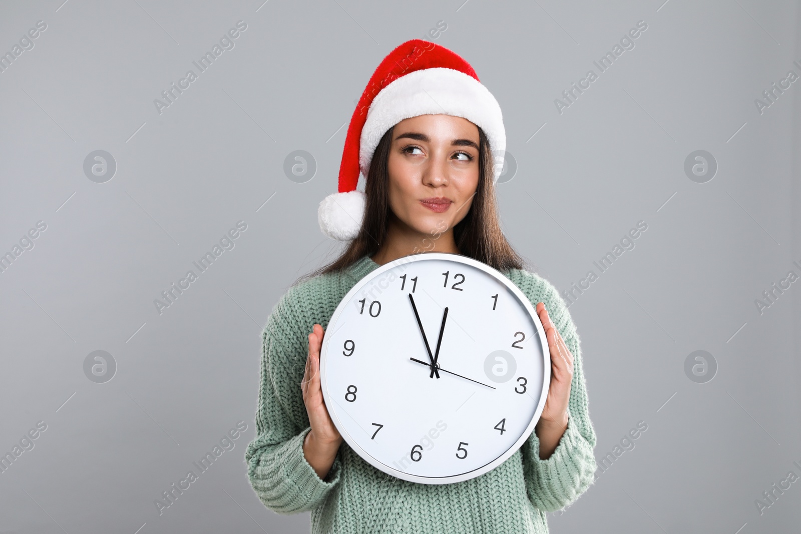 Photo of Woman in Santa hat with clock on grey background. New Year countdown