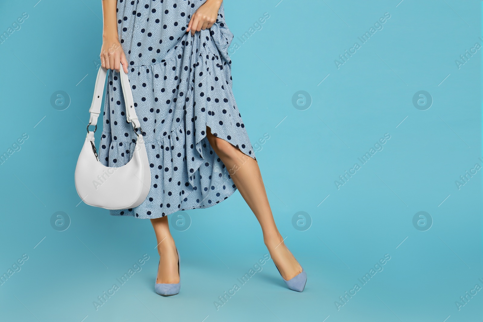 Photo of Woman with stylish bag on light blue background, closeup. Space for text