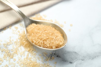 Photo of Spoon with brown sugar on white marble table, closeup. Space for text