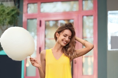 Happy young woman with cotton candy outdoors