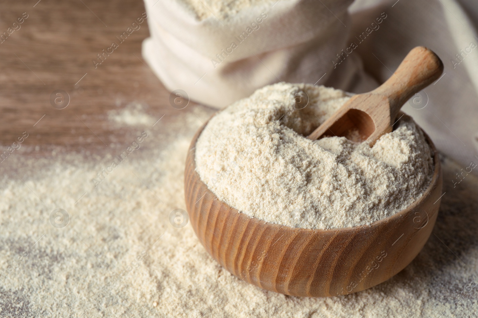 Photo of Wooden bowl with quinoa flour and scoop on table. Space for text