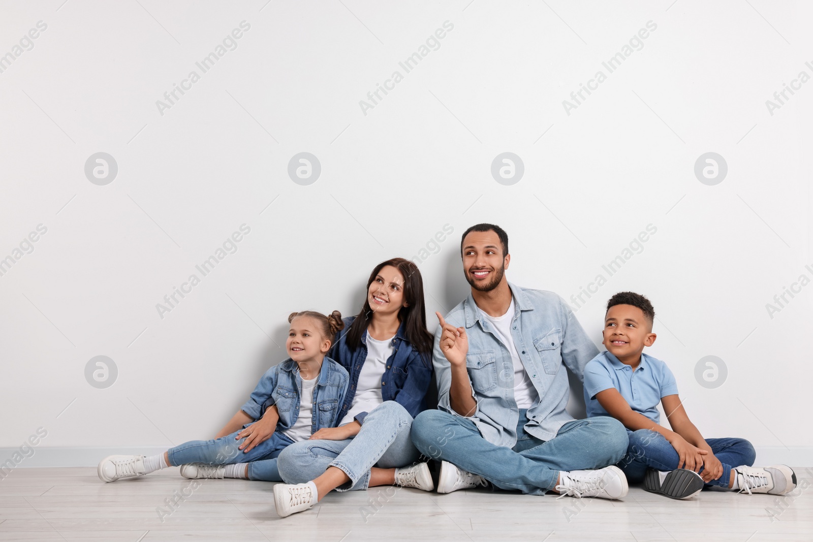 Photo of Happy international family sitting near white wall