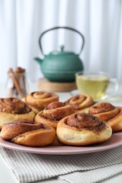 Photo of Many tasty cinnamon rolls on white table, closeup. Space for text