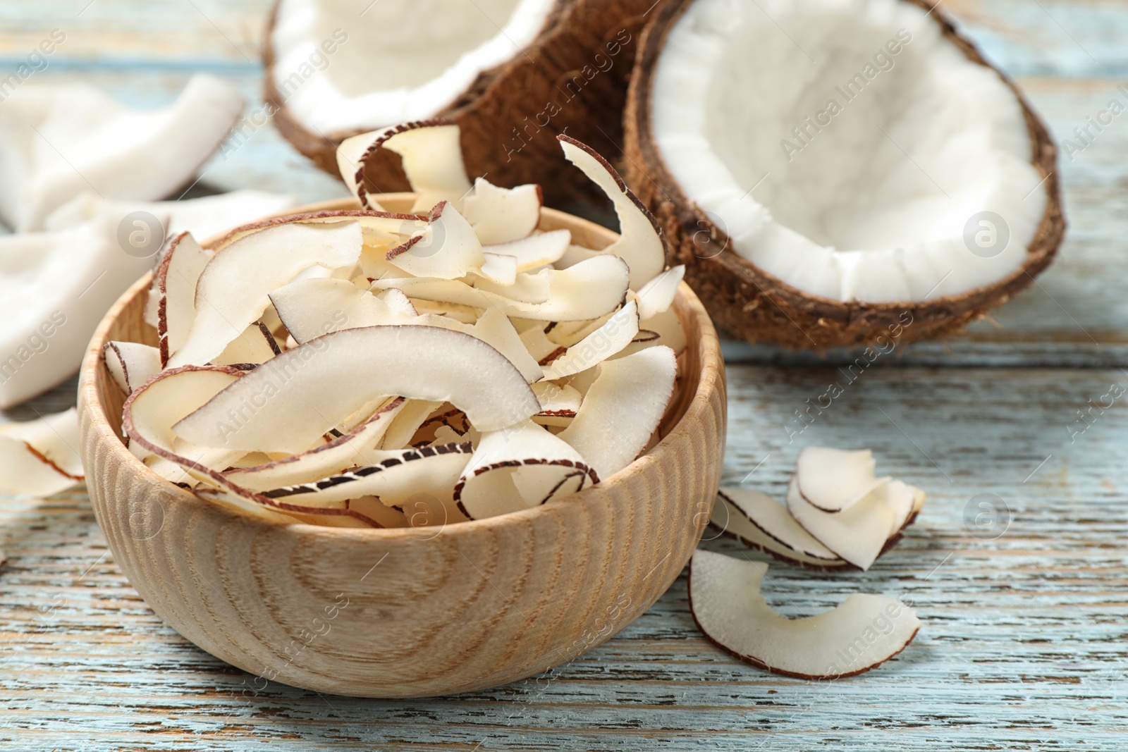 Photo of Tasty coconut chips on light blue wooden table