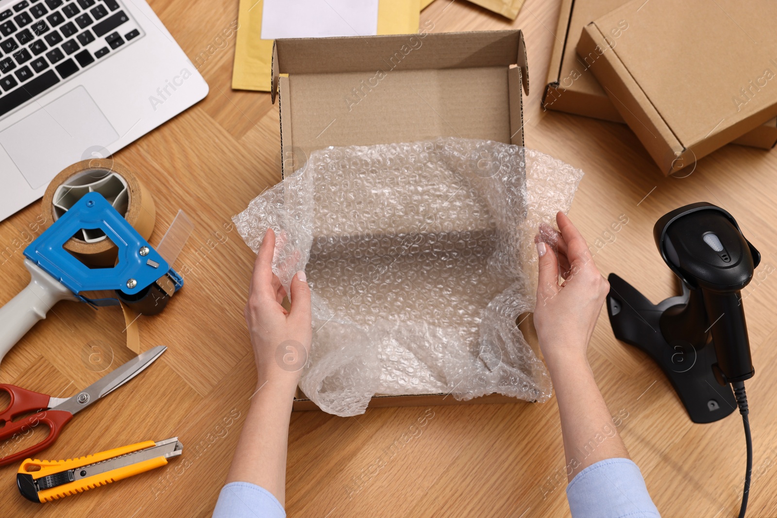 Photo of Post office worker packing parcel at wooden table, top view