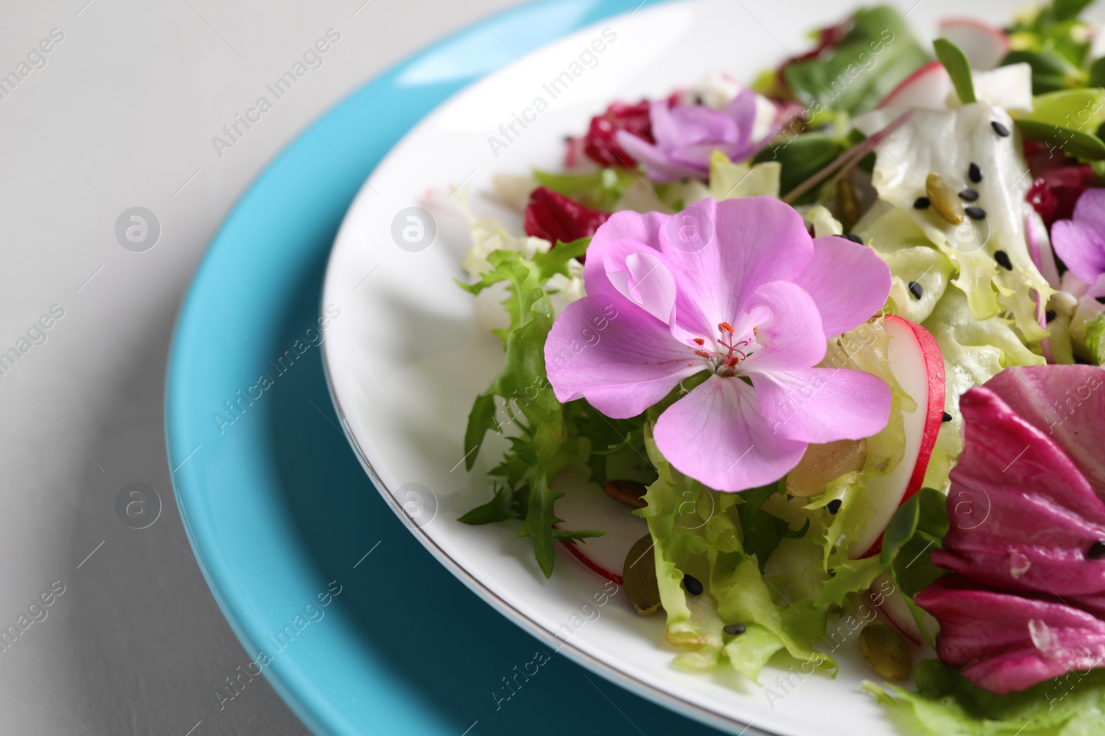 Photo of Fresh spring salad with flowers on grey table, closeup
