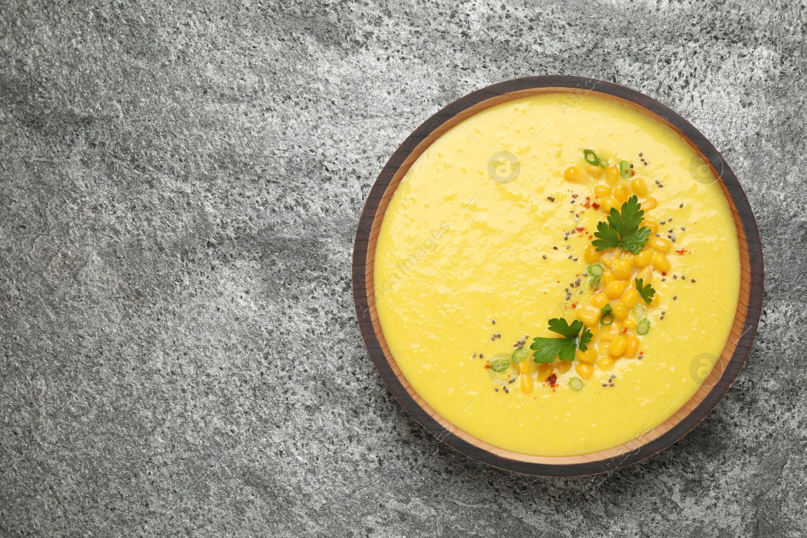 Photo of Delicious creamy corn soup on grey table, top view. Space for text