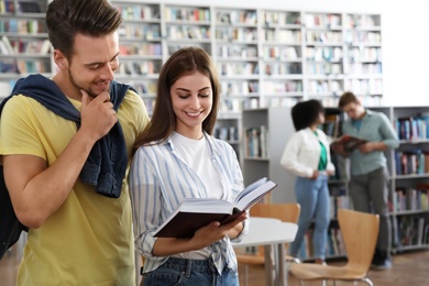 Photo of Happy young people with book in library