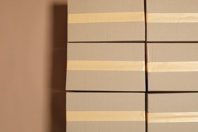 Cardboard boxes on light brown background, flat lay. Space for text