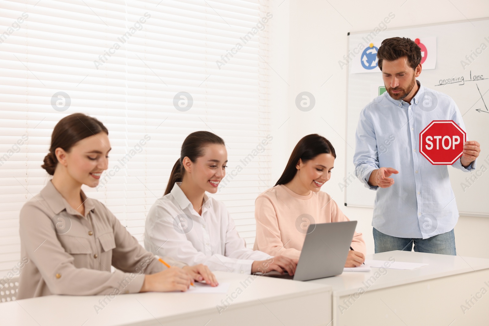 Photo of Teacher showing Stop road sign during lesson in driving school