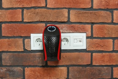Photo of Compact electric heater charging from socket indoors