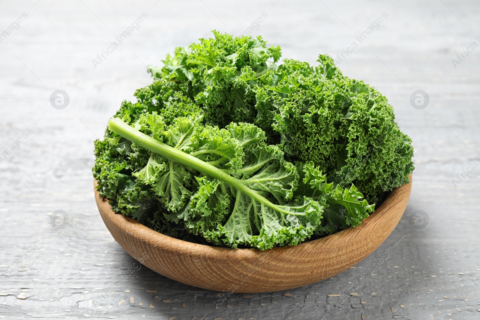 Photo of Fresh kale leaves on light grey wooden table