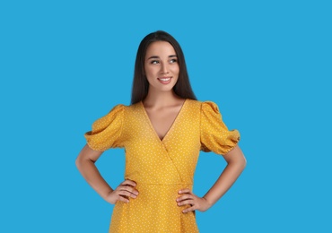 Photo of Young woman wearing yellow dress on light blue background