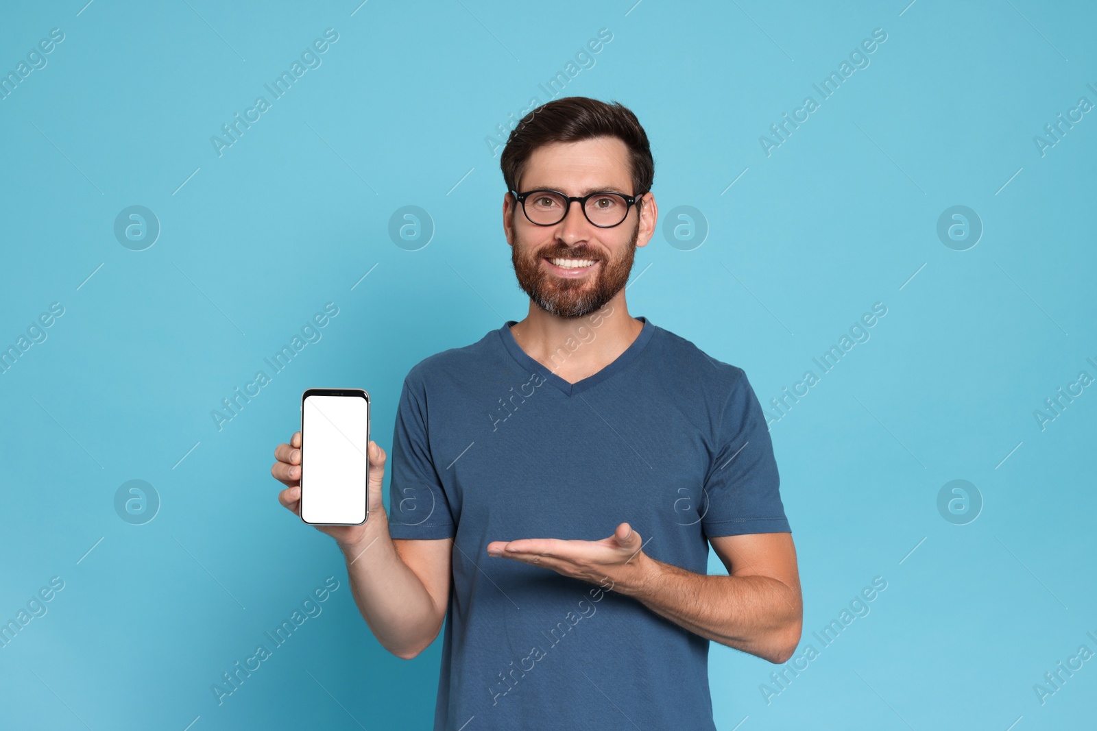 Photo of Happy man showing smartphone on light blue background