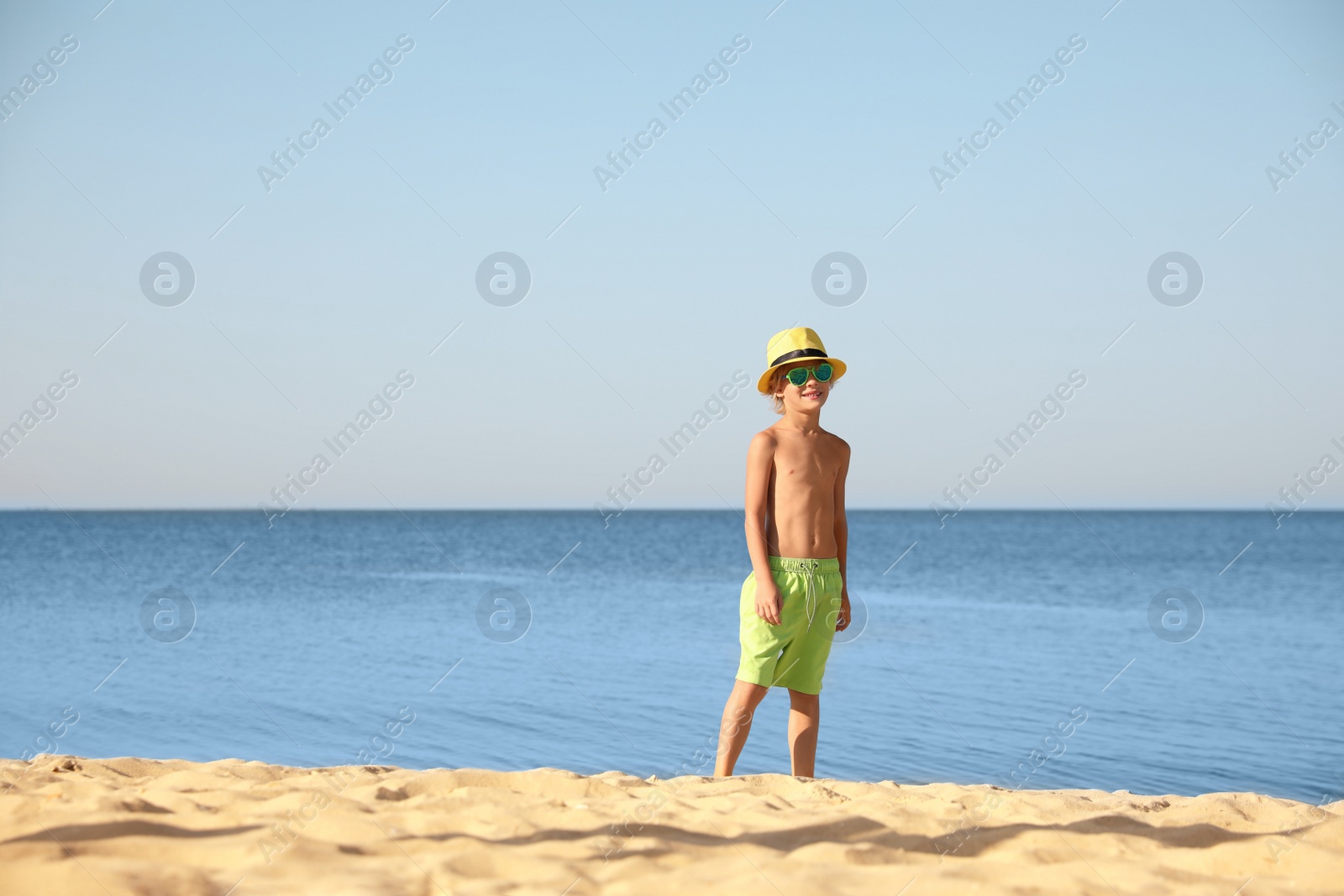 Photo of Cute little child at sandy beach on sunny day