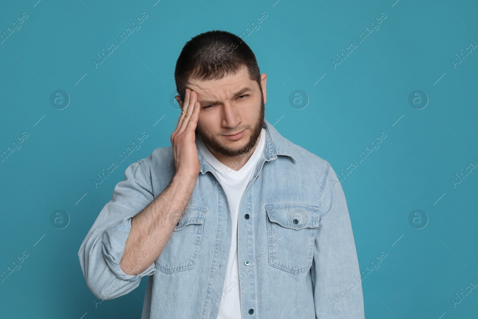 Photo of Man suffering from headache on light blue background