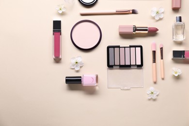 Photo of Flat lay composition with different makeup products and beautiful spring flowers on beige background