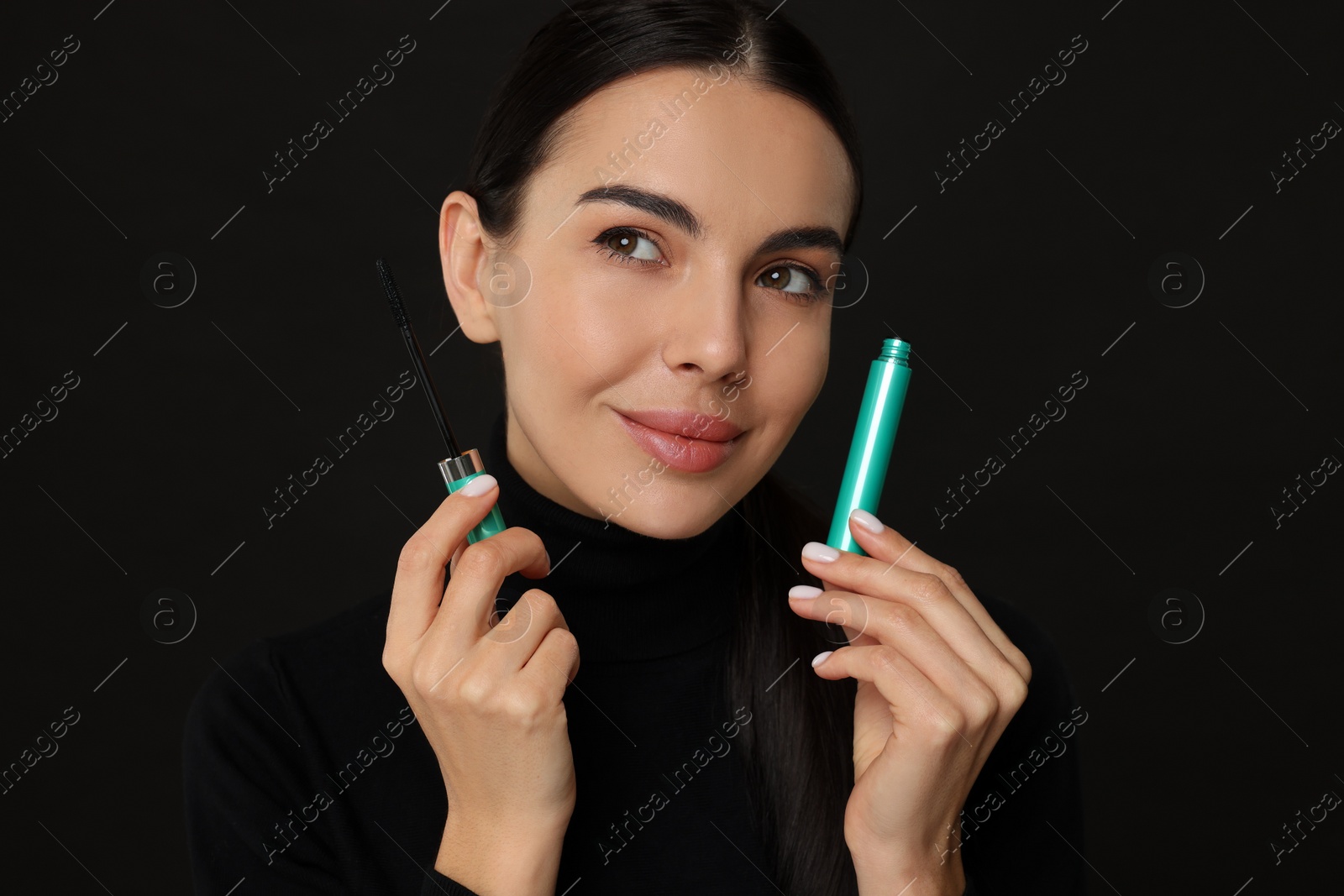 Photo of Beautiful young woman with mascara on black background