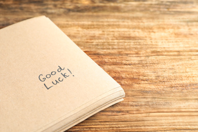 Photo of Notebook with phrase GOOD LUCK on wooden table, closeup. Space for text