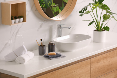 Toiletries and stylish vessel sink on light countertop in modern bathroom