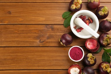 Purple mangosteen powder and fruits on wooden table, flat lay. Space for text