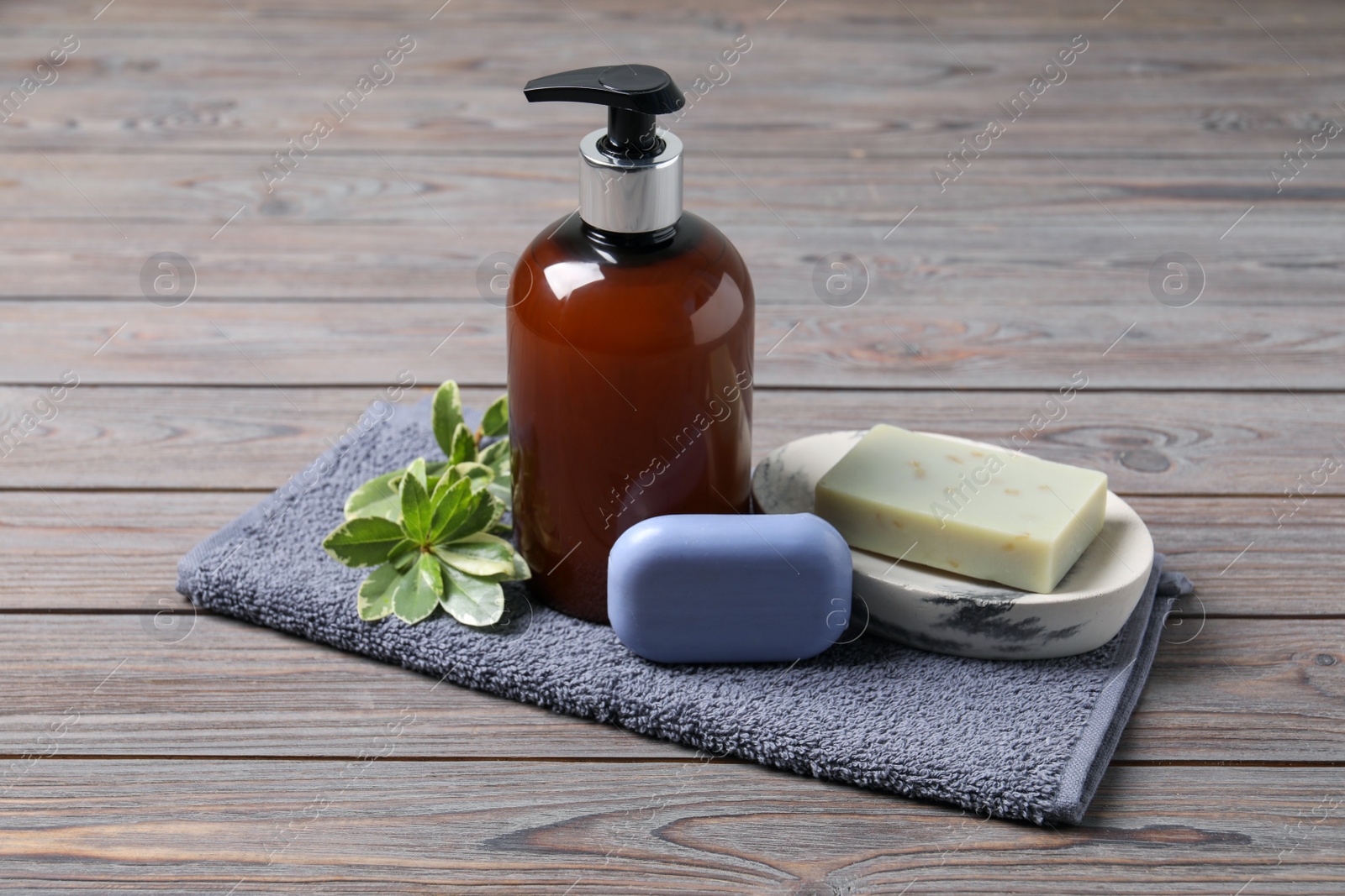 Photo of Soap bars, dispenser and terry towel on wooden table,