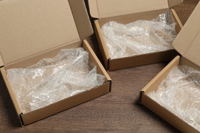 Many open cardboard boxes with bubble wrap on wooden table