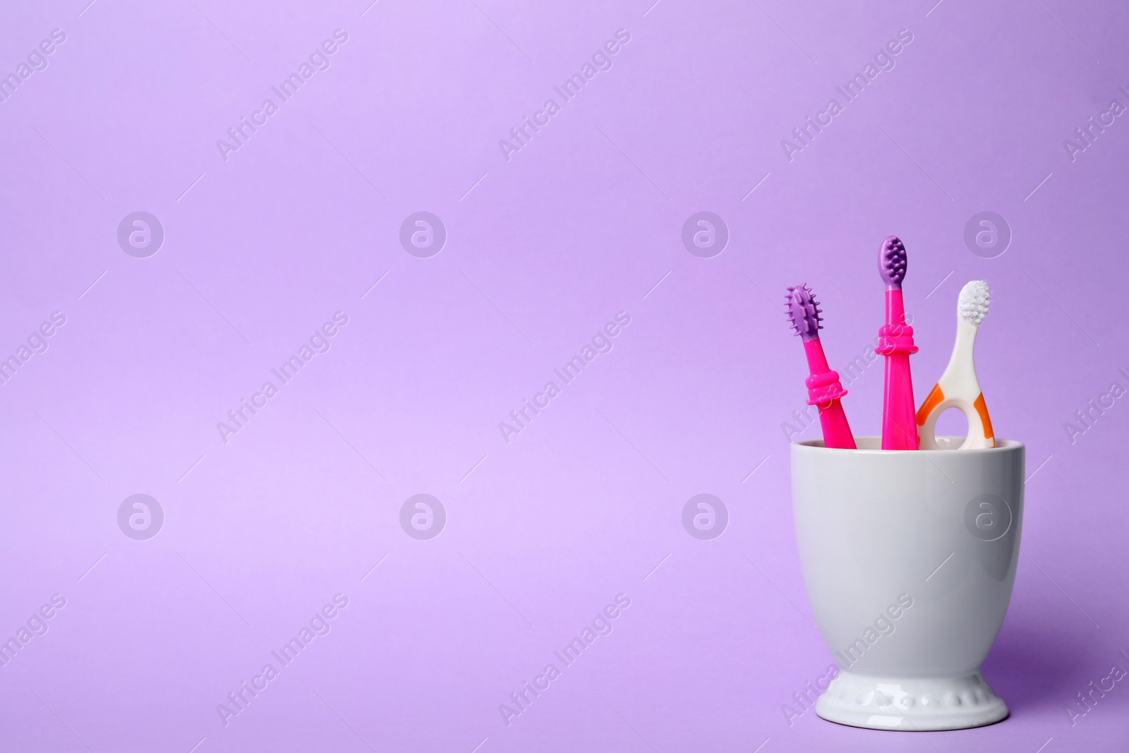 Photo of Baby toothbrushes in holder and space for text on color background