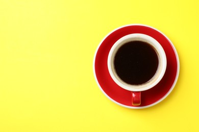 Photo of Aromatic coffee in cup on yellow background, top view. Space for text