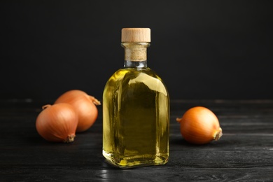 Glass bottle of onion syrup and fresh vegetable on dark table