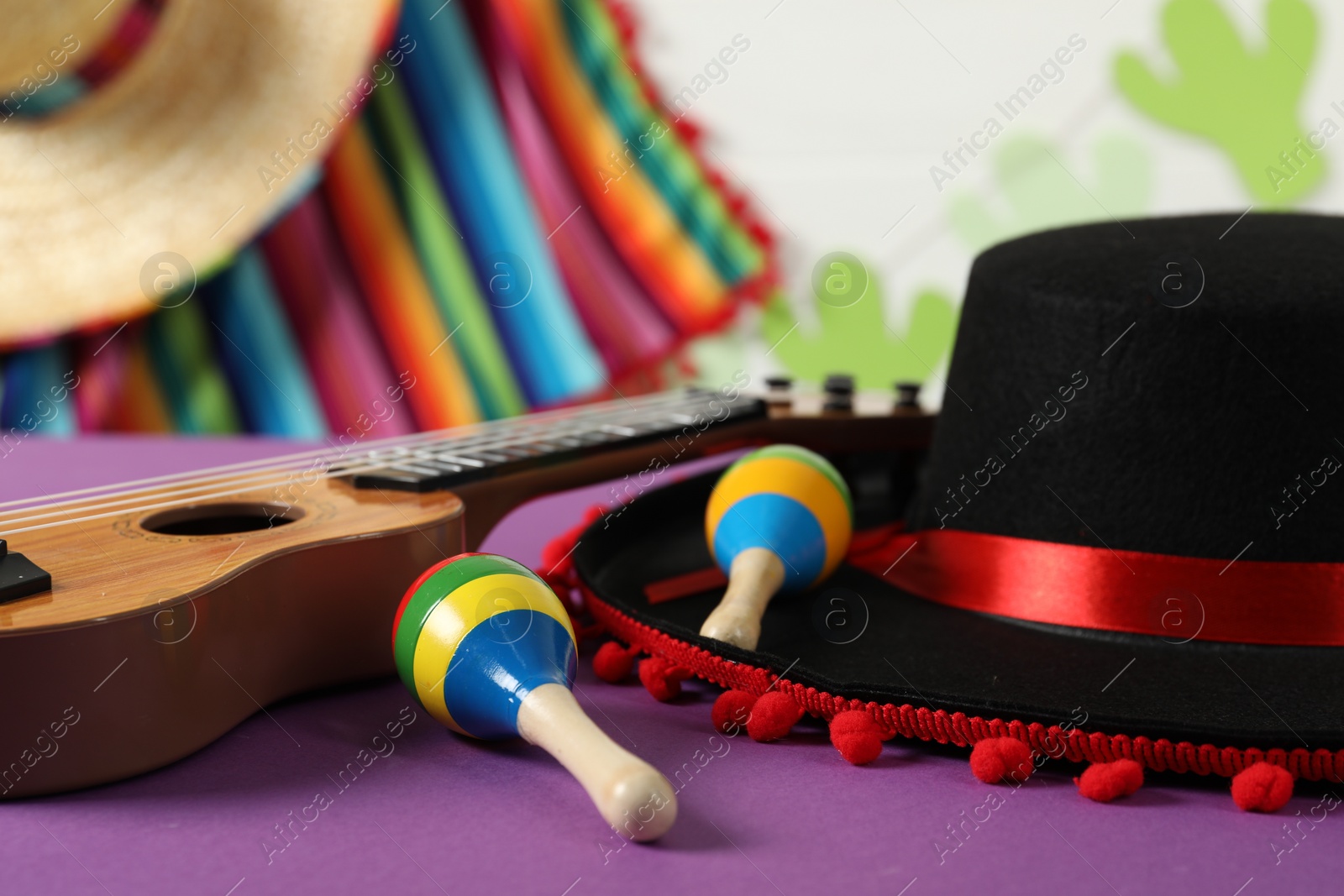 Photo of Black Flamenco hat, ukulele and maracas on purple table, closeup