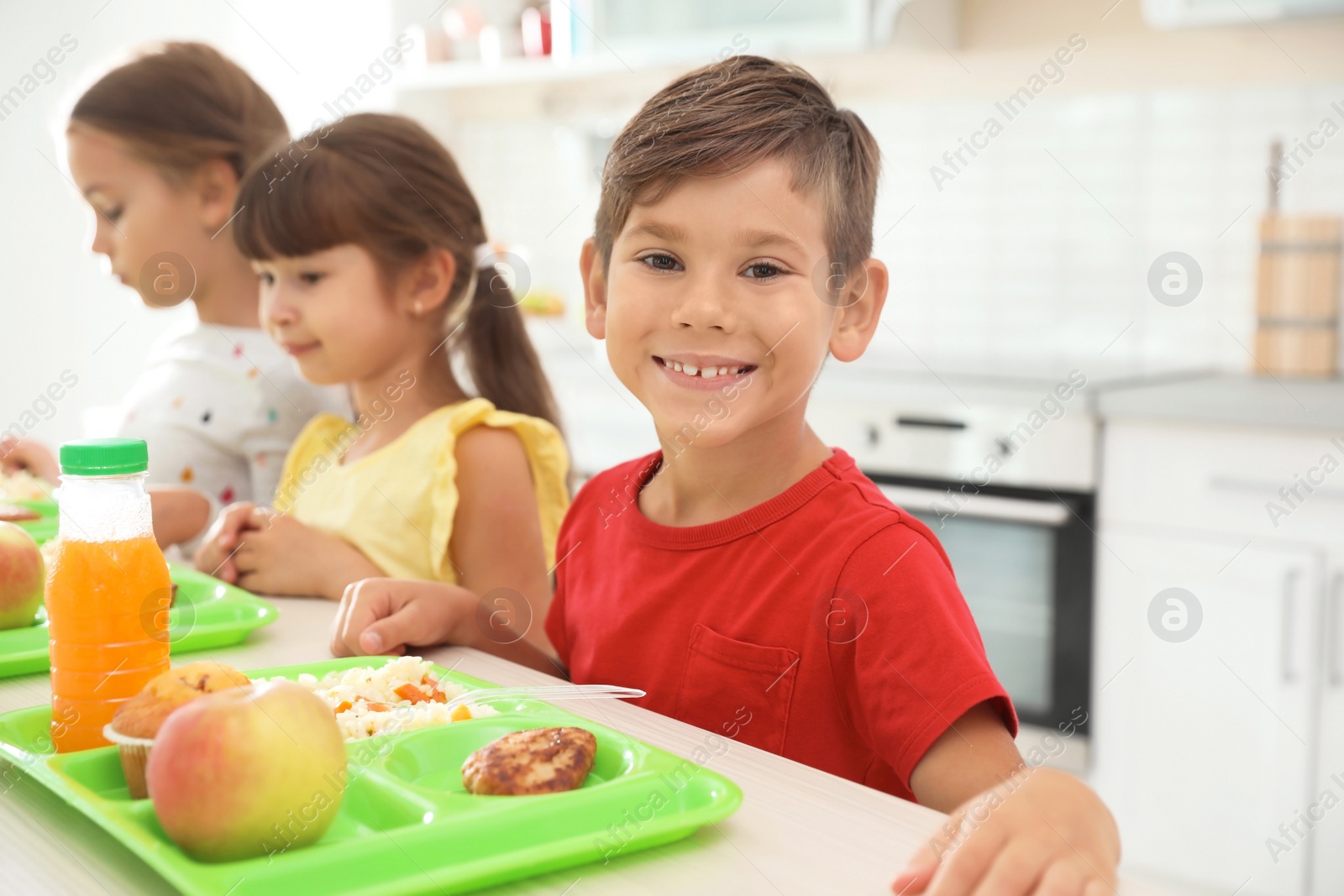 Photo of Children sitting at table and eating healthy food during break at school