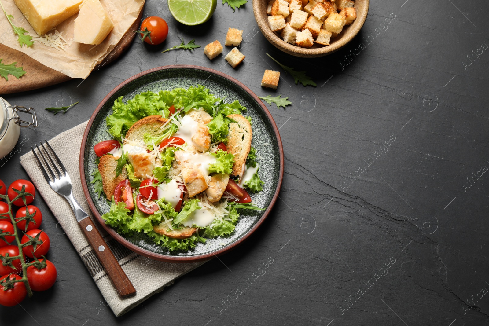 Photo of Delicious fresh Caesar salad on black table, flat lay. Space for text