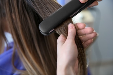 Photo of Professional hairdresser working with client in salon