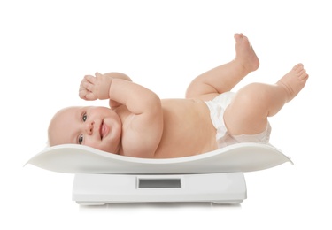 Photo of Cute little baby lying on scales against white background