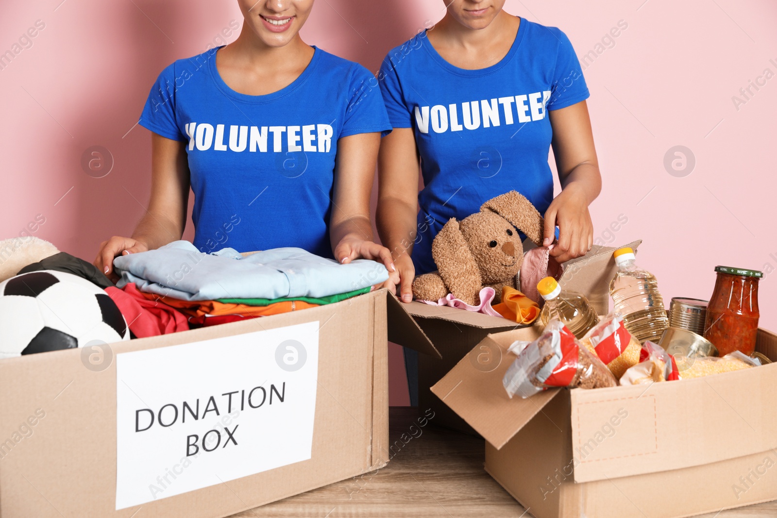 Photo of Young volunteers collecting donations at table on color background