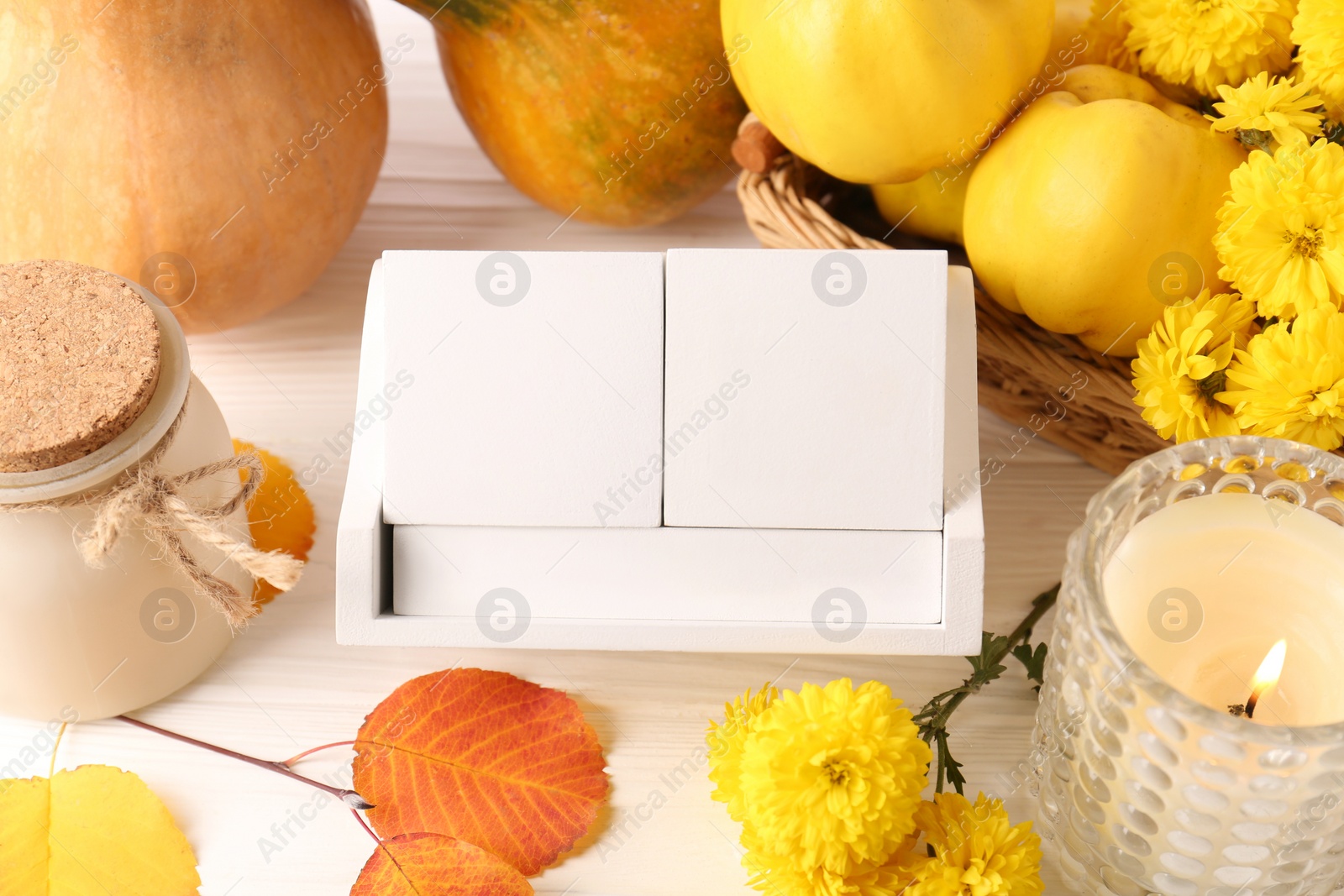 Photo of Thanksgiving day, holiday celebrated every fourth Thursday in November. Block calendar, candle, pumpkins, quinces and chrysanthemum flowers on white wooden table