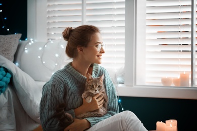 Photo of Young woman with cute cat at home. Cozy winter